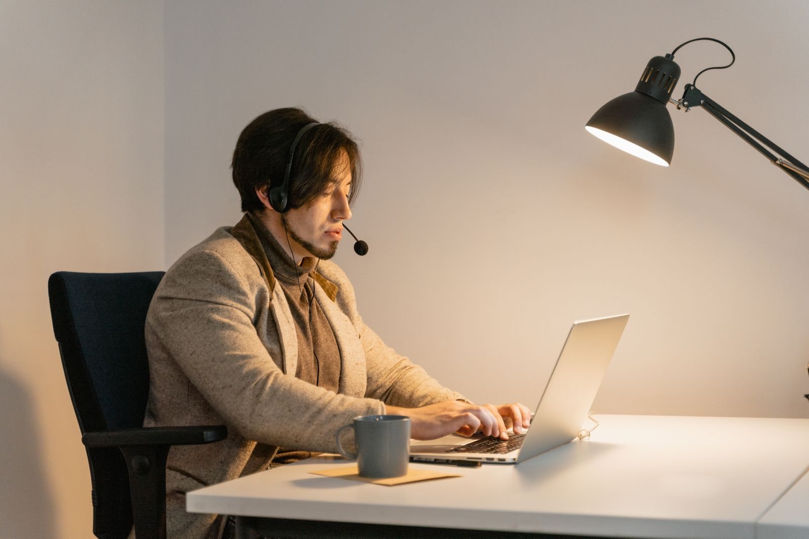 A professional with a headset working late under a desk lamp