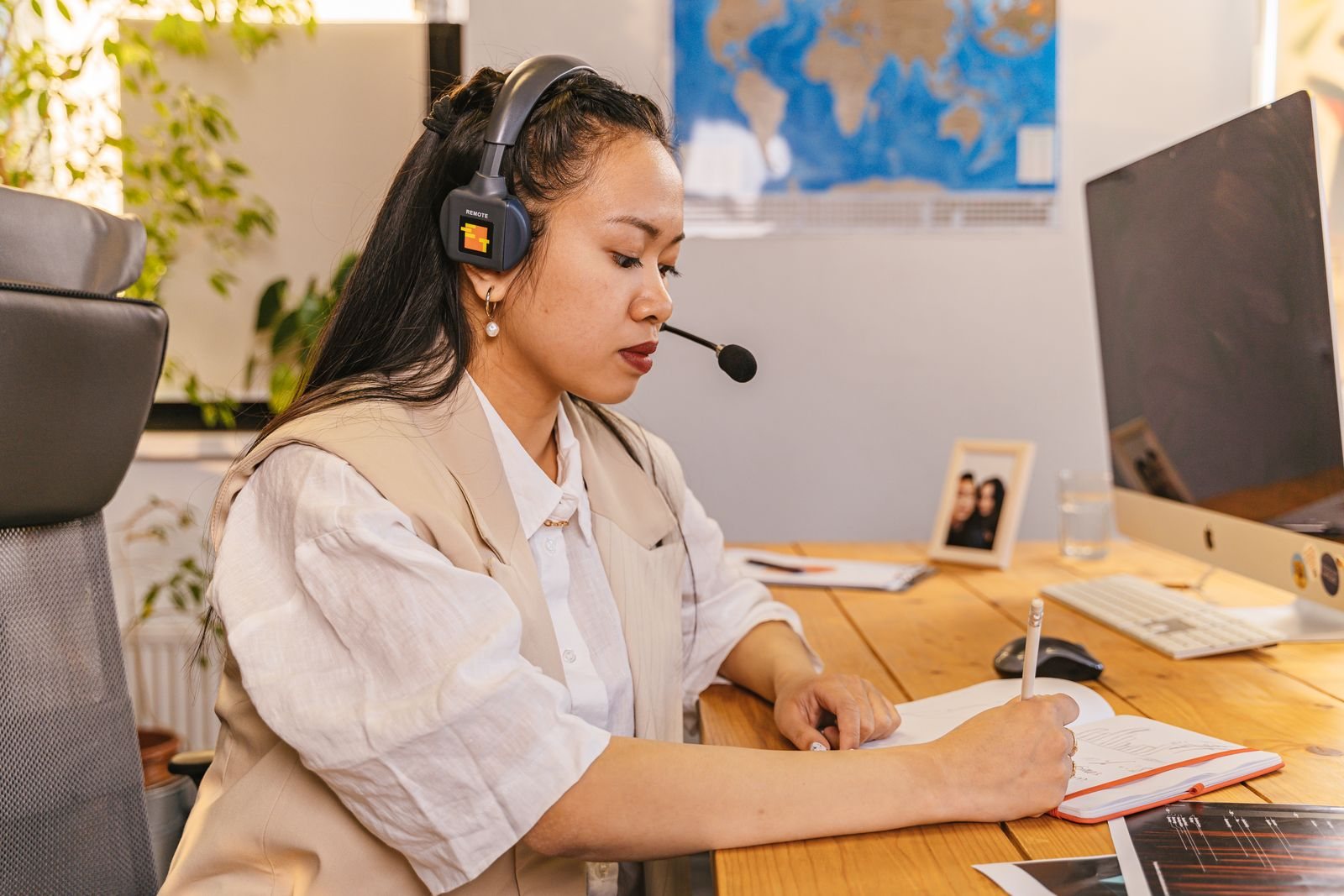 An interpreter with a headset taking notes at her desk