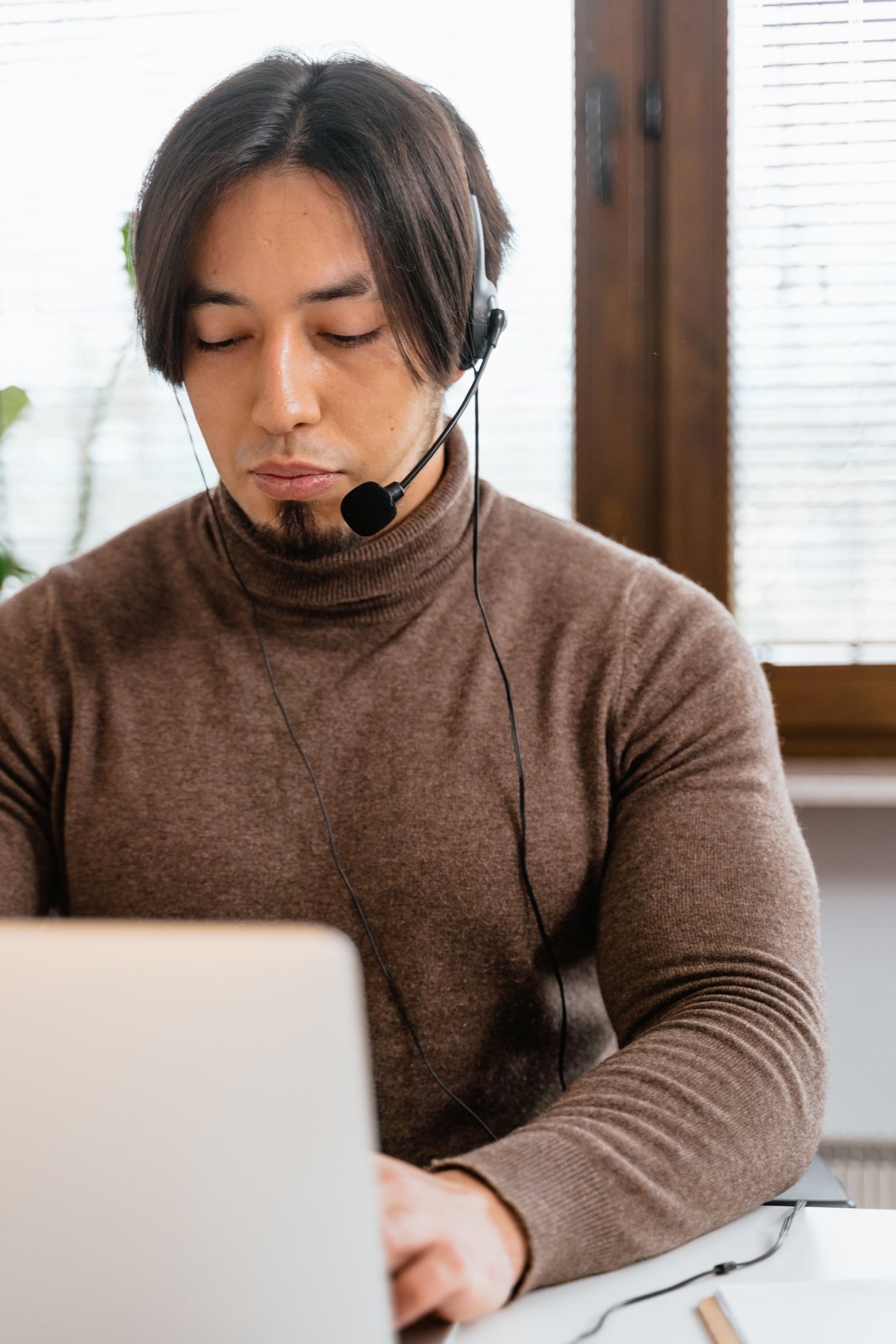 A language professional with a headset working at his laptop